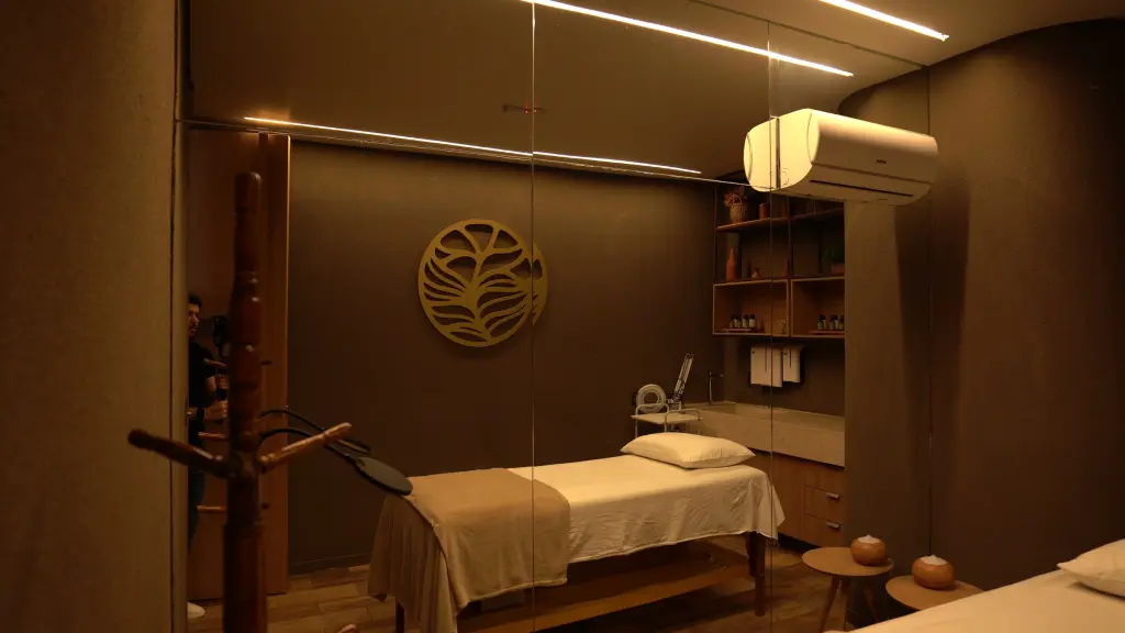 Sala de massagem da PUR, com maca, luz quente e o símbolo dourado na parede